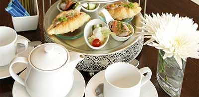 Afternoon tea, with cup, pot of tea, croissants and snacks