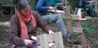 a woman crafts wood in a field