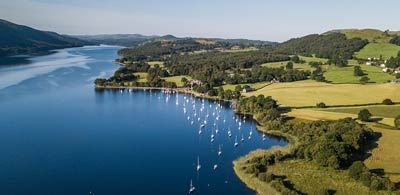 aerial view of Coniston Water with boats, surrounded by trees 