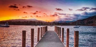 The pier at Lake Windermere with a orange and pink sunset 