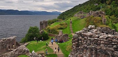 People walking the paths around the cobbled ruins of Urquhart Castle