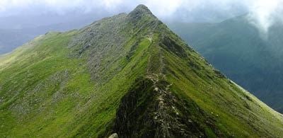 Grassy peak of helvellyn mountain against a heavy cloudy sky 