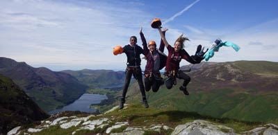 A group of people jumping int he air at the top of a large hill of Honiston Slate mines