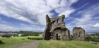 acient ruins in the green park of Holyrood against a cloudy blue sky