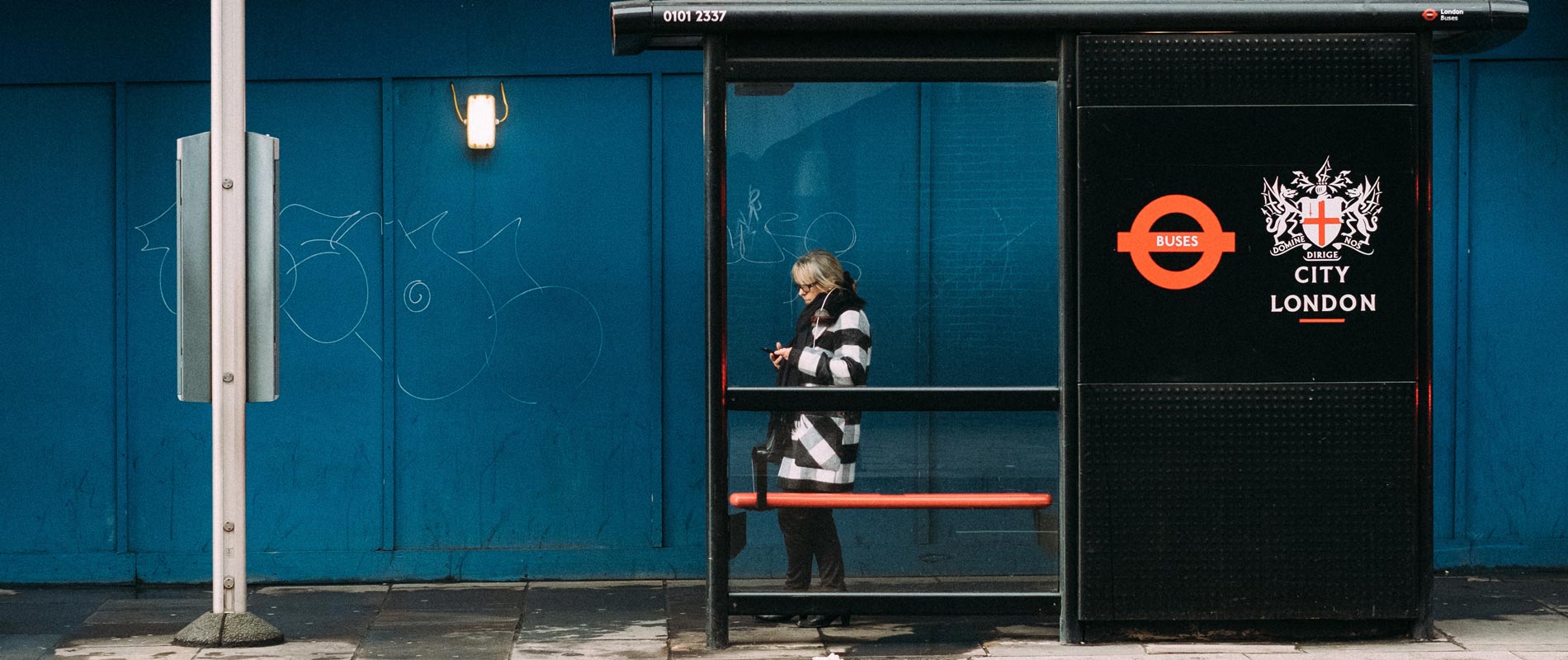 woman looking at her phone while waiting at a bustop 