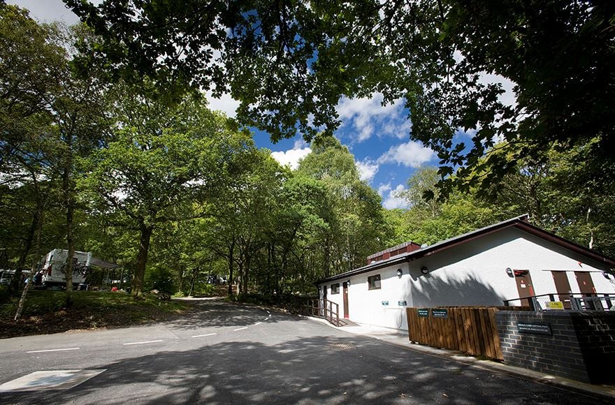 White reception building of Coniston Park Coppice campsite surrounded by trees