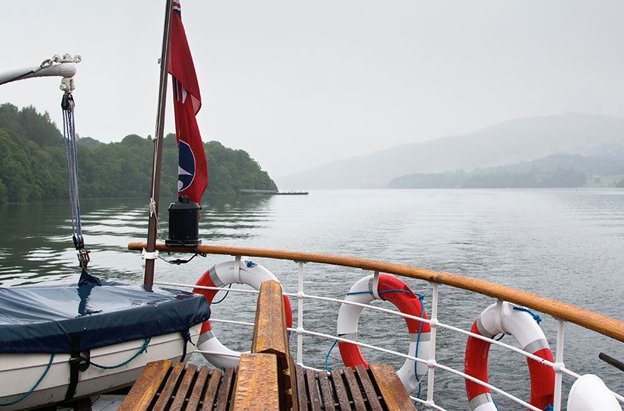 The deck of a boat lined with life aids looks out of over the calm waters of Lake Winderemere