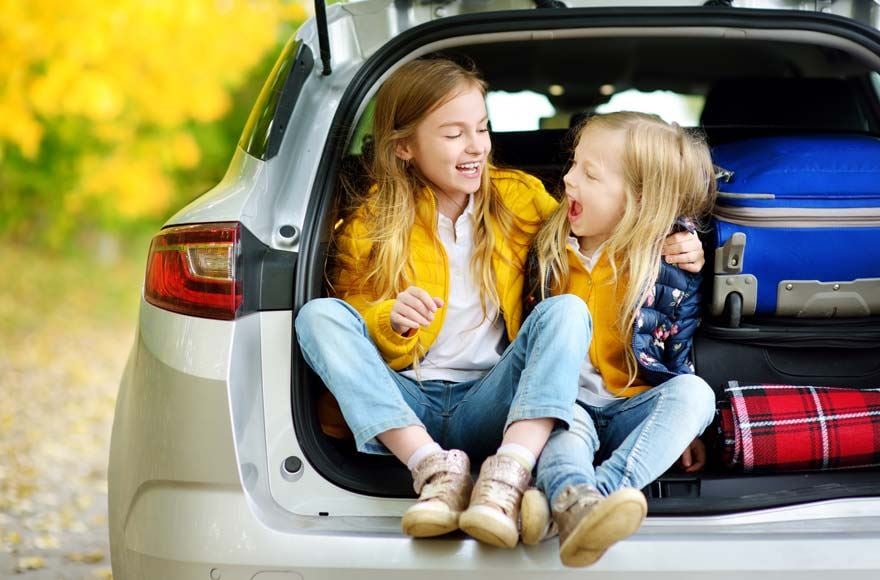 Young girls wearing yellow in the boot of a car