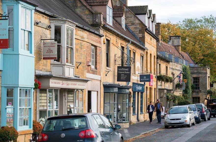 The colourful high street shops of Moreton-in-Marsh on a raod with parked cars