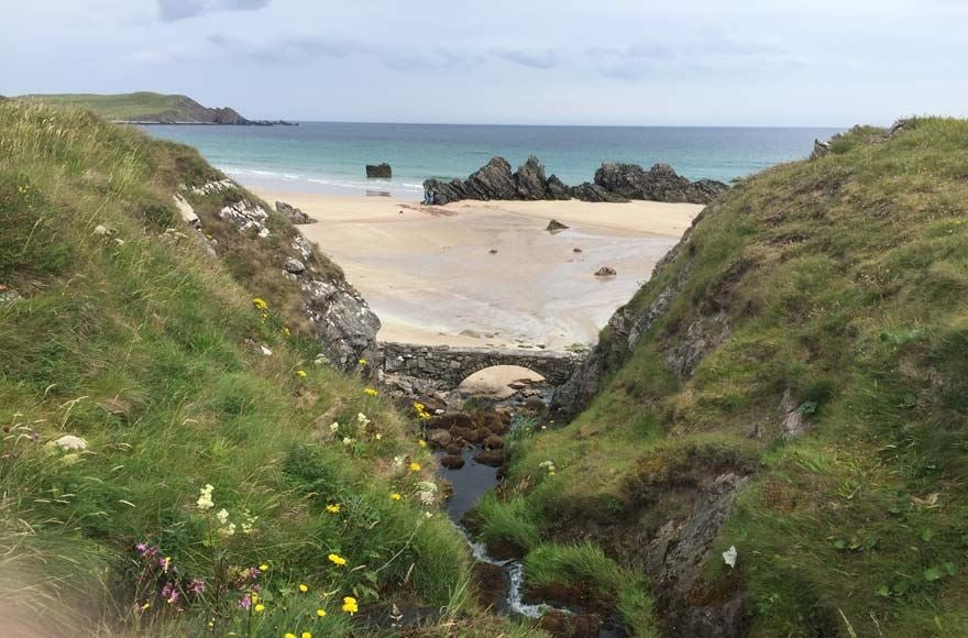 Grassy mounds and rocks on sandy beach at Sango Bay