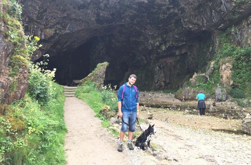 Man and dog standing outside Smoo Cove