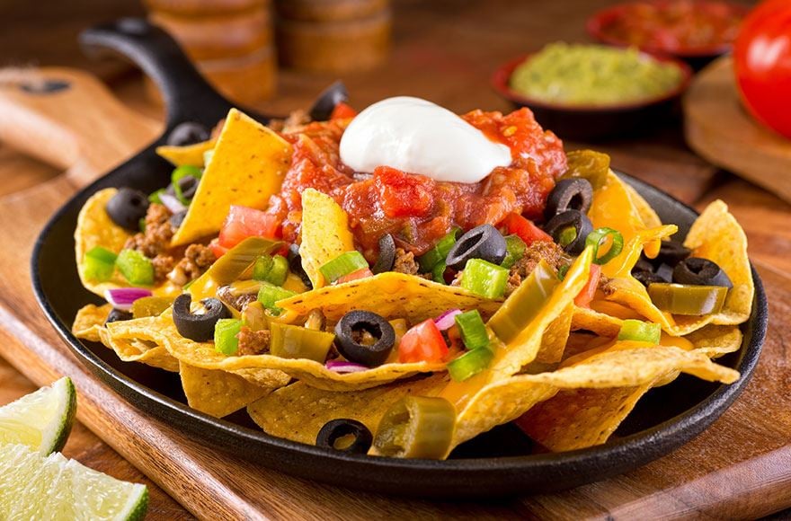 Nachos served on an iron skillet with block olives, sour cream and chilli sauce 