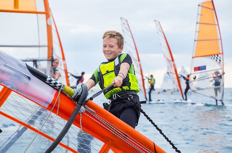 Boy windsurfing on a lake with other windsurfers