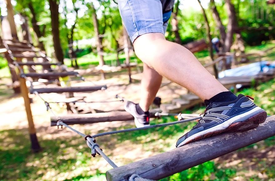 A person walking arocross a rope bridge in the forest 