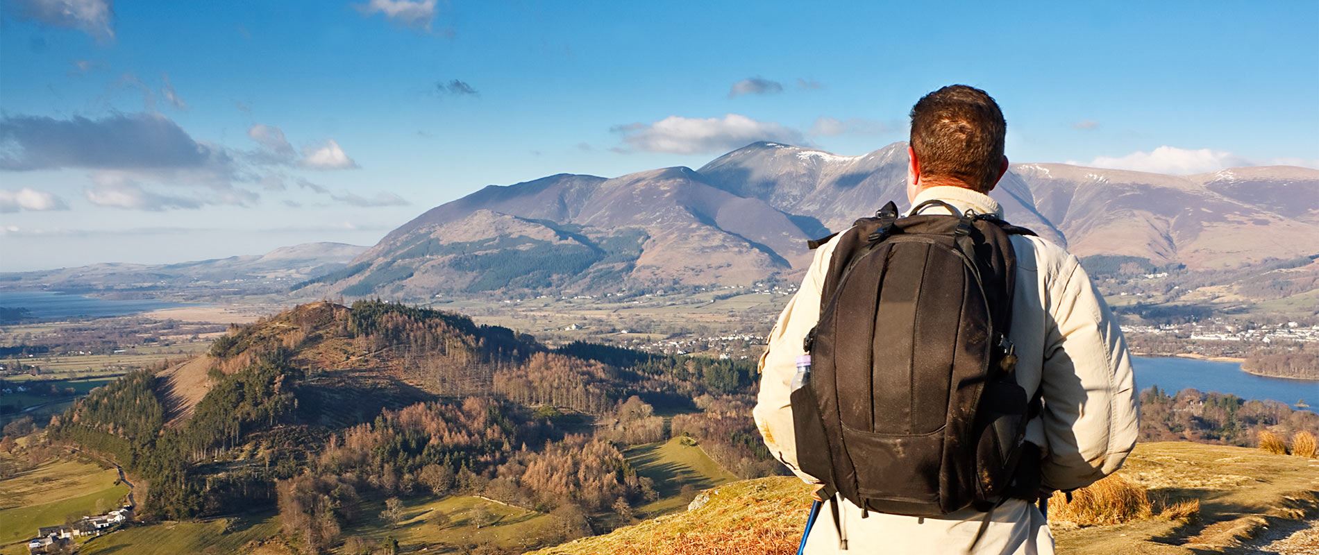 A man standing at the top of The Old Man of Coniston looking out at the view