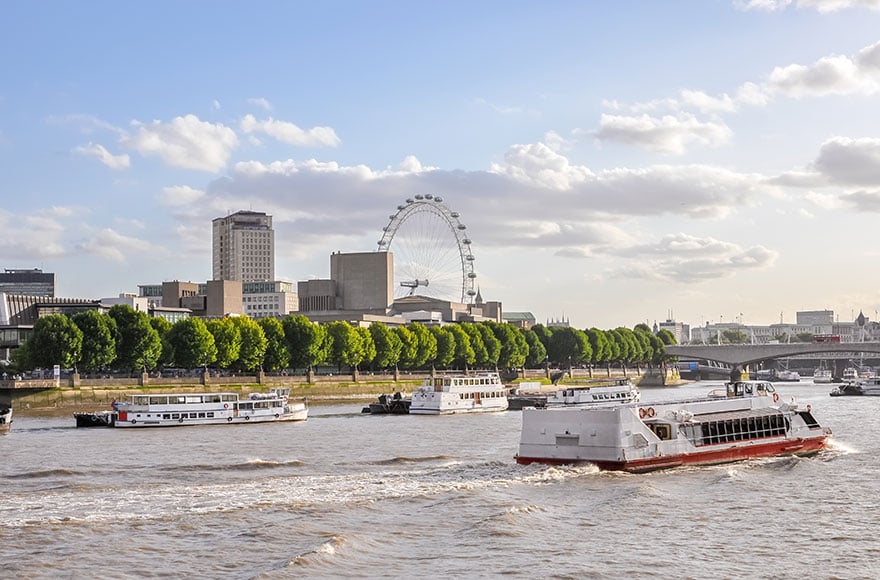 boats on the river thames lined with tall buildings and the London Eye 