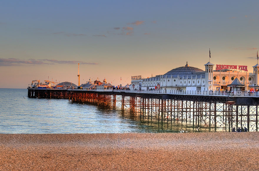 pebble beach and calm sea with Brighton Pier at sunset 