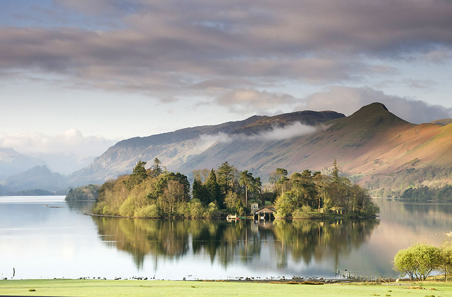 derwentwater lake with a small island is trees, surrounded by large hills 