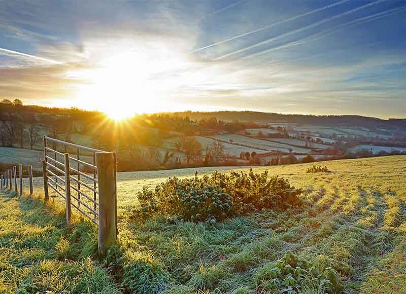 The sun rising above frosty fields in the countryside