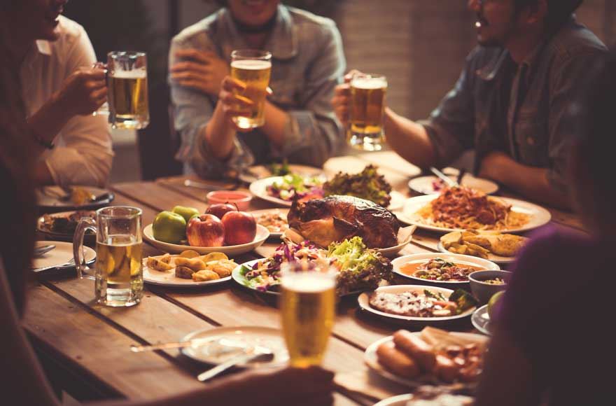 Several people gathered around a table with food and drinks in a cosy countryside pub