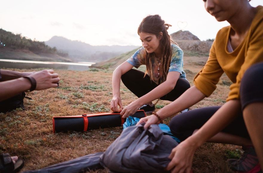 Group of campers packing away their tent next to lake