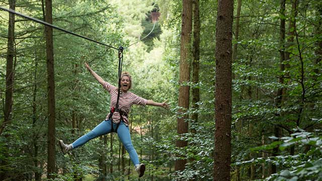 A woman having fun on a zipwire through the trees