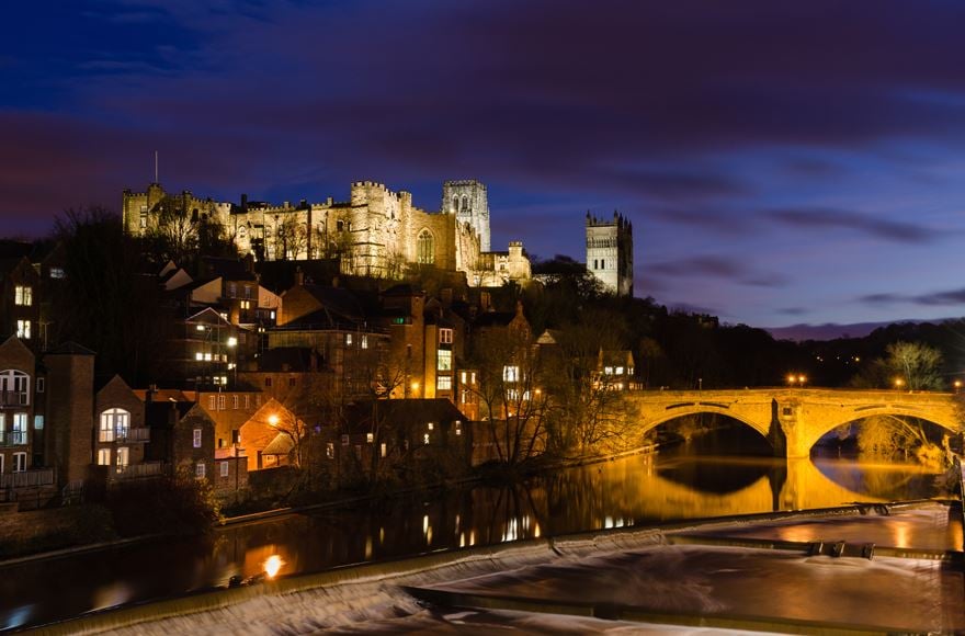 Durham Castle, Cathedral and medieval Framwellgate bridge lit up at dusk