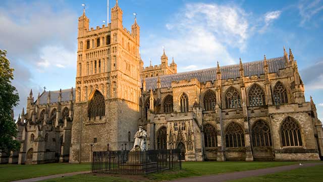 Facade of Exeter Cathedral seen in the sunshine against a bright blue sky