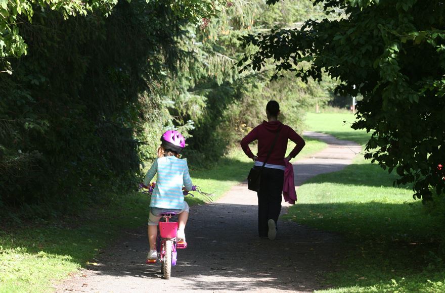 Child on bicycle and walker on forest track at Forfar Lochside