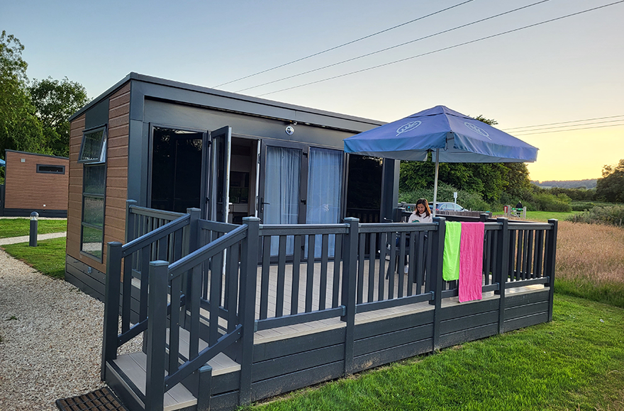 A woman relaxing outside ont he decking of her glamping pod