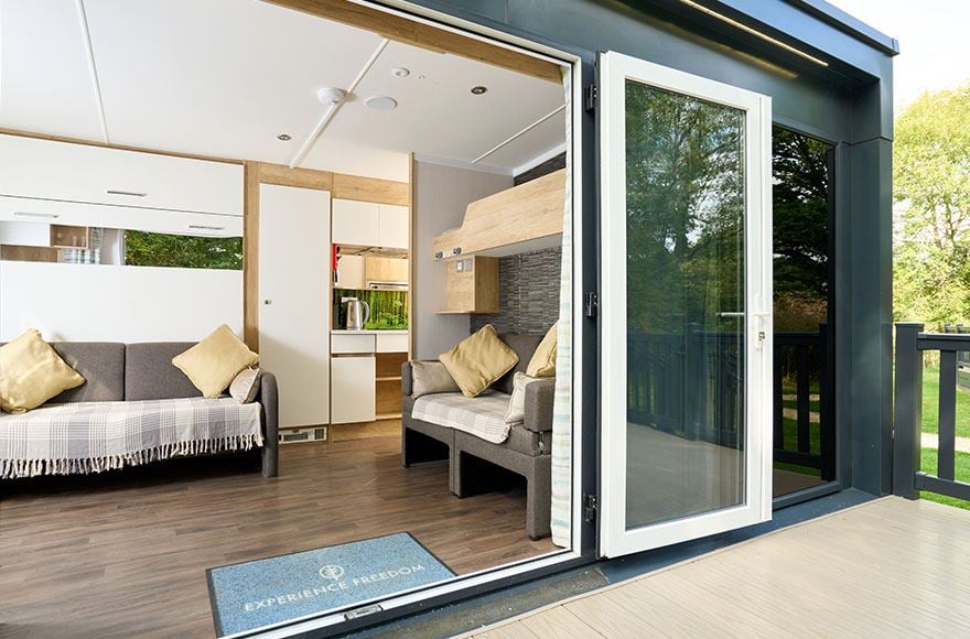 Open doors of a glamping pod showing sofas and kitchen area