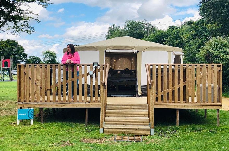 Exterior of a yurt showing a woman relaxing on the decking 