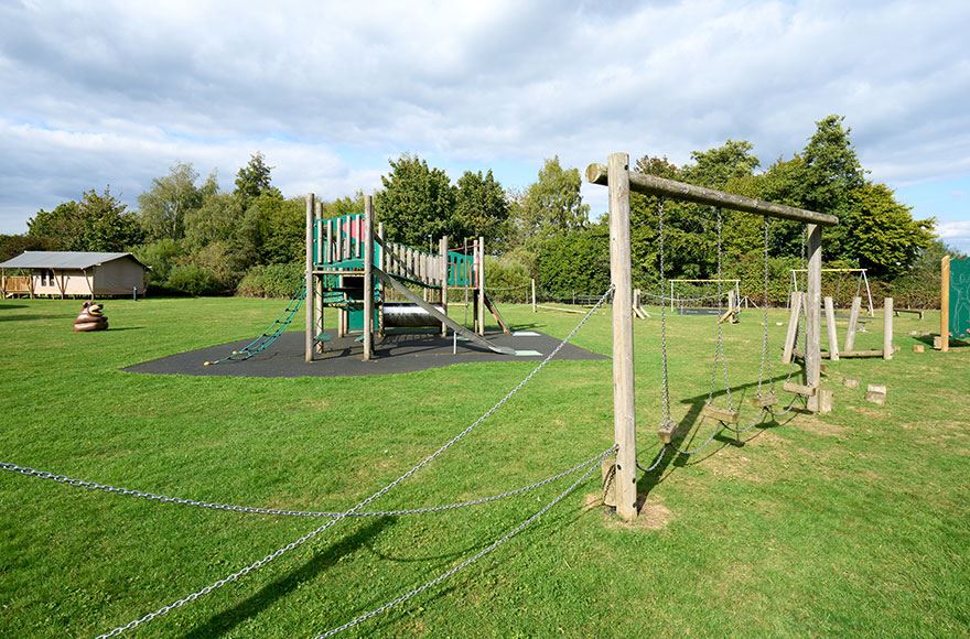 Wooden play area activites including a slide and ropes 