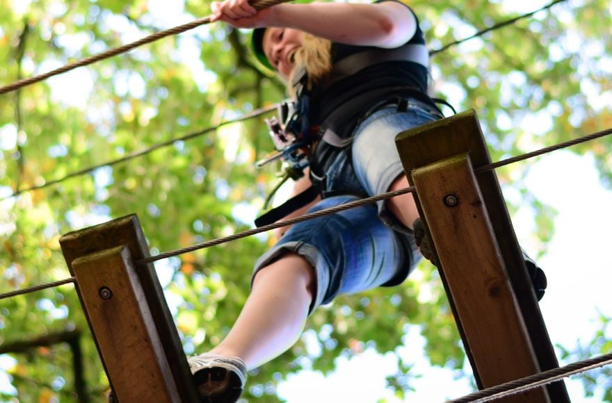 girl smiling on high ropes tree-top adventure course