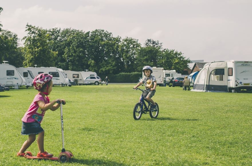 Children playing on field with bike and scooter