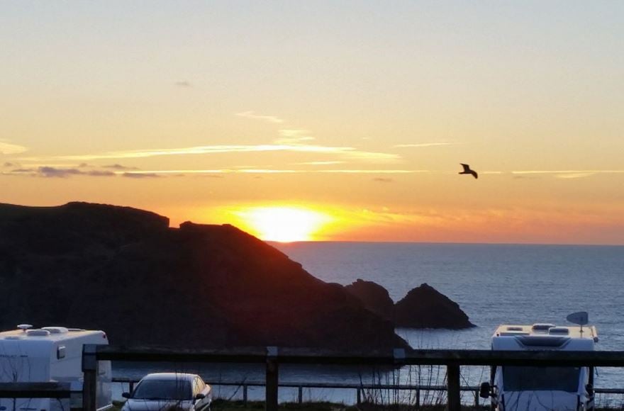 parked motorhomes and cars overlooking a sea sunset 