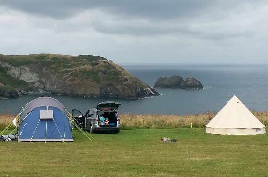 two tents pitched up on a grassy field overlooking Sea views from Trewethett campsite