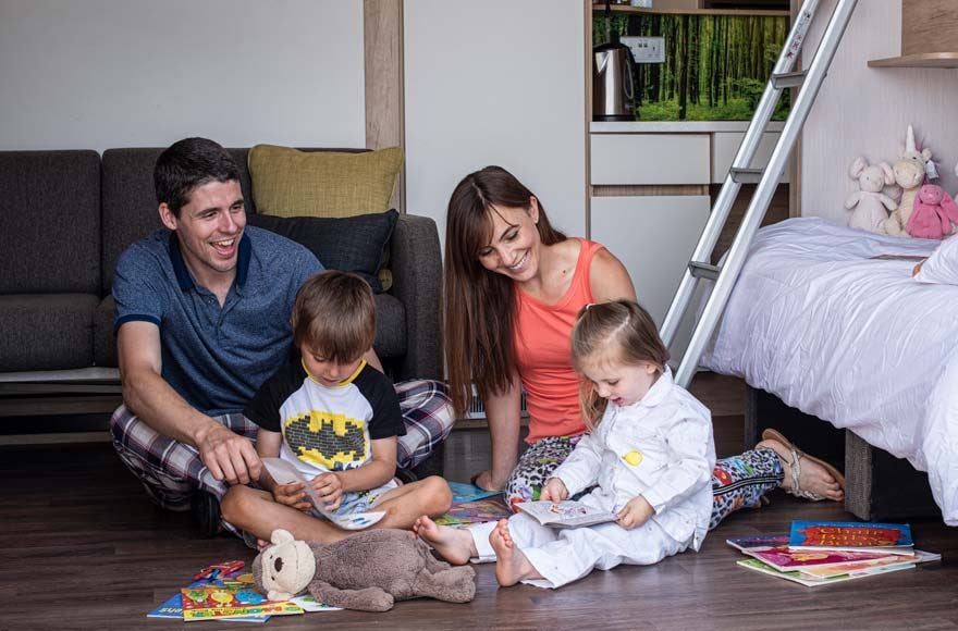 family reasing books on the floor of their cosy glamping pod