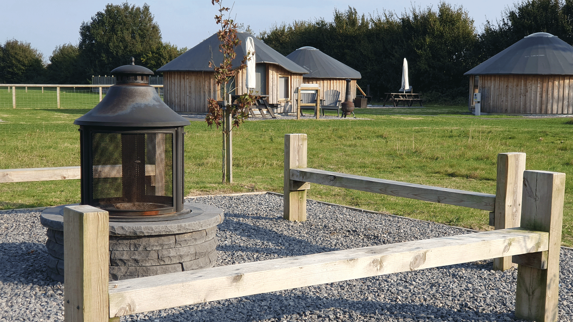 Wooden yurts surrounding a communal fire pit area at Daleacres Experience Freedom campsite.