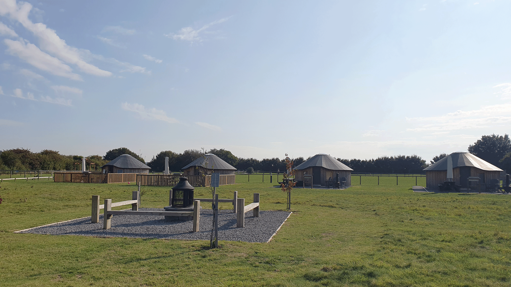 Several wooden yurts in the Kent countryside at Daleacres Experience Freedom campsite.