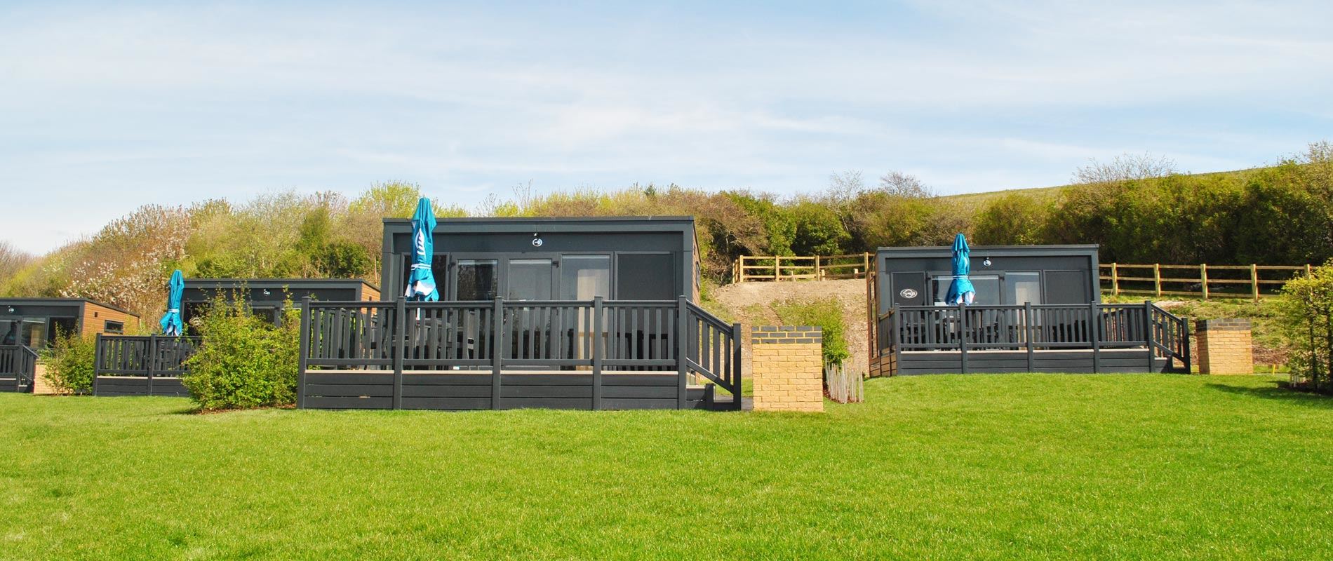 A scenic view of a glamping pod located on a grassy hill, showcasing its inviting exterior and the surrounding pastoral landscape.