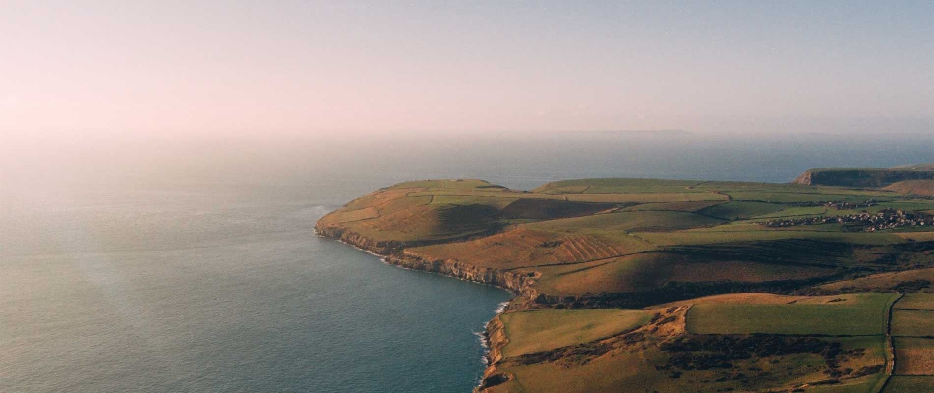 the dancing ledge in Swanage with sweeping green fields surrounded by a calm sea  