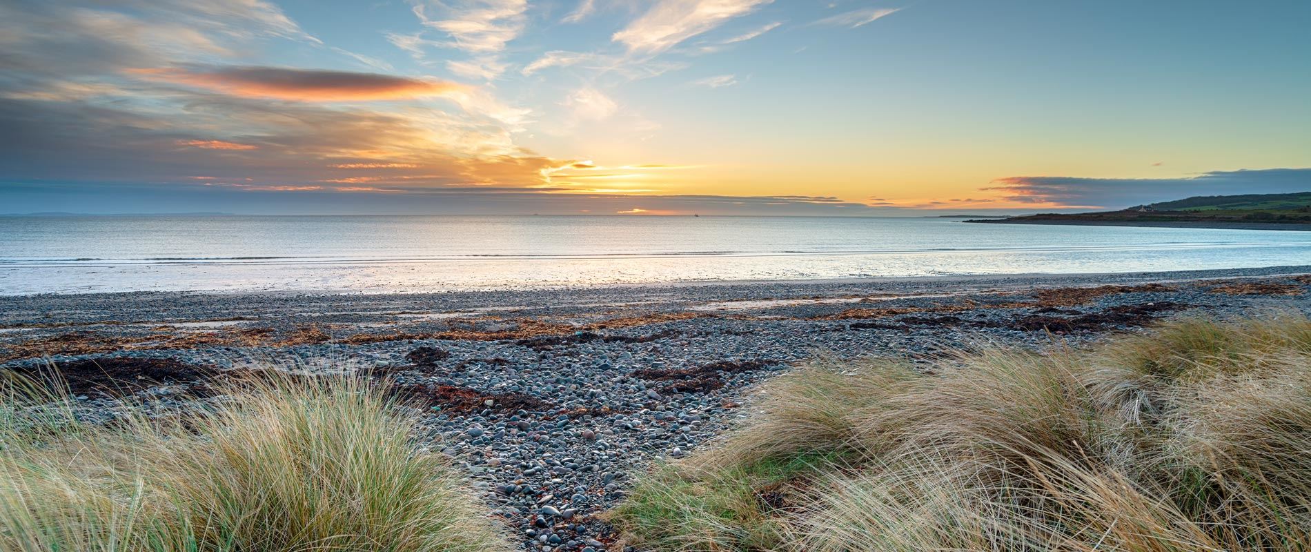 sunset landscape of New England Bay at sunset showing calm seas and shingle beach 