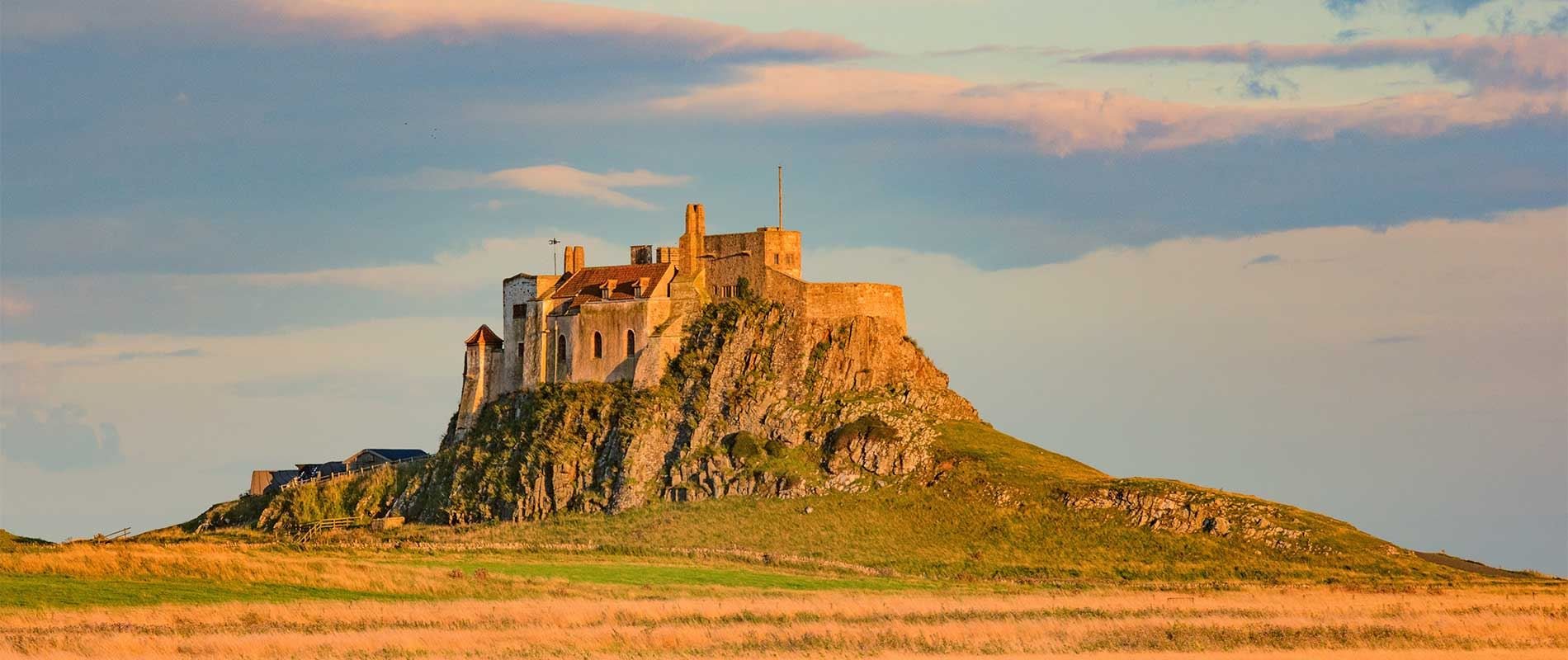 a stone built house sits atop  hill basking in golden sunlight