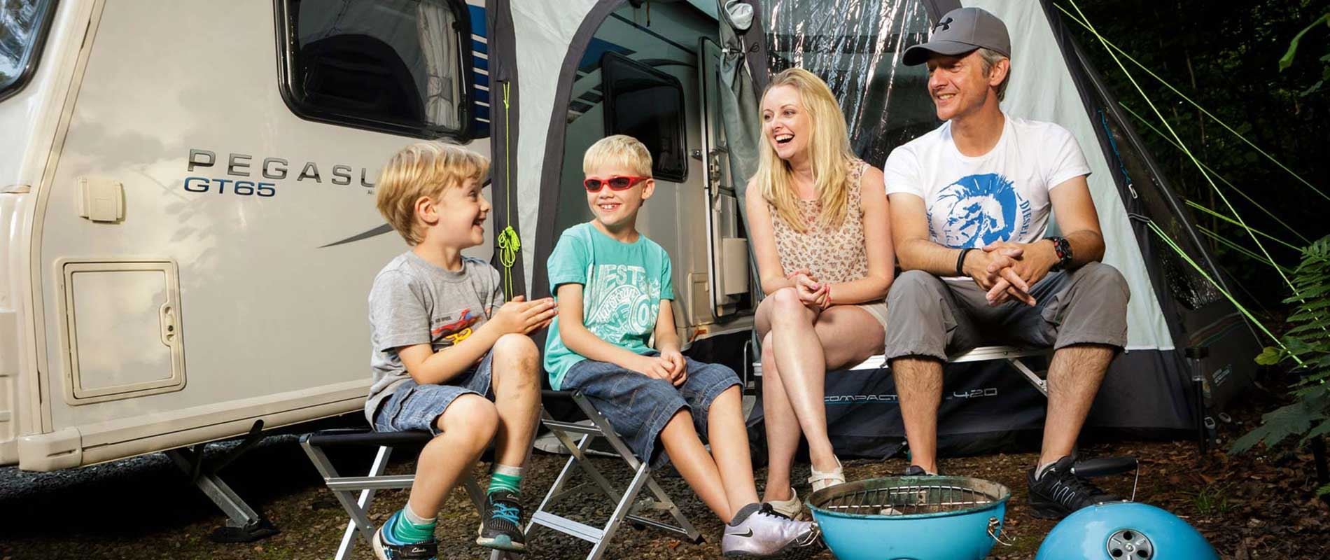 family enjoying a barbeque outside their awning tent and caravan