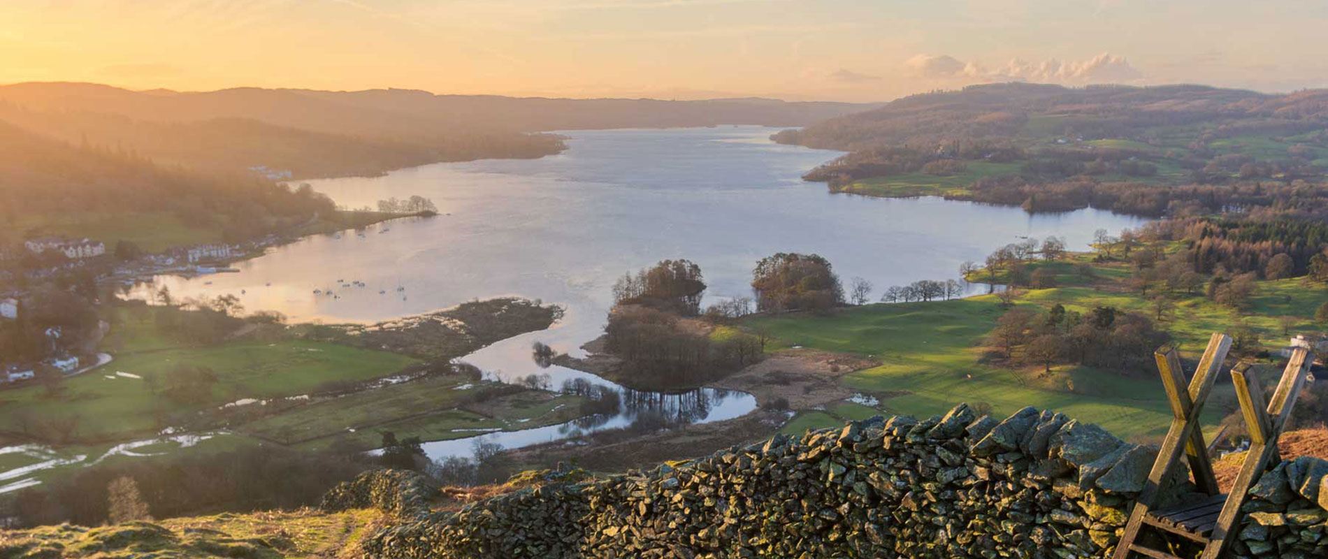 lake windermere during sunrise with a stone wall and gate 