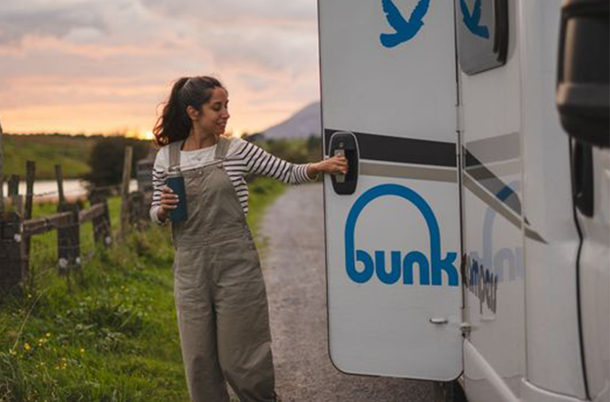 woman opening the door of her bunk motorhome 