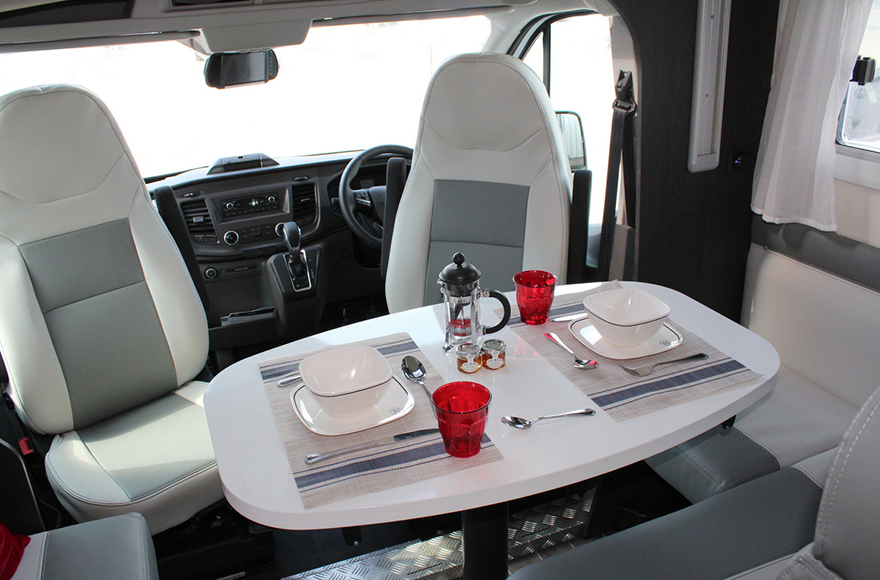 dining area of campervan showung front chairs turned around with dining table 