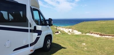 Motorhome parked on grass overlooking the sea