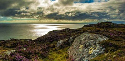 a moody sunrise showing the rocky edge and clam water of Lochinver